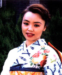 A woman in a colorful traditional kimono smiling outdoors.